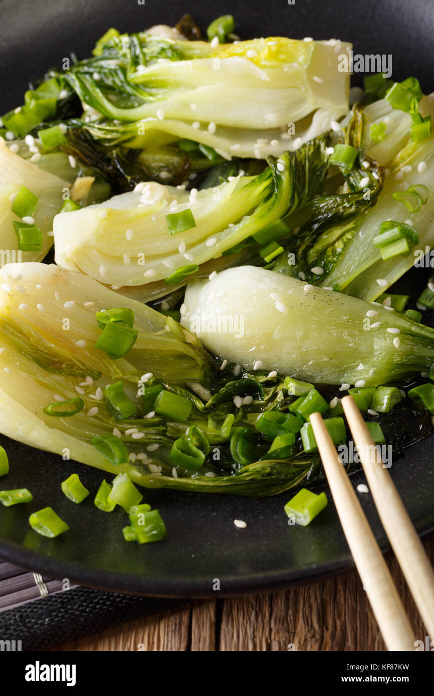 Frittura di cavolo cinese con zenzero, aglio, i semi di sesamo e le cipolle verdi close-up su una piastra verticale. Foto Stock