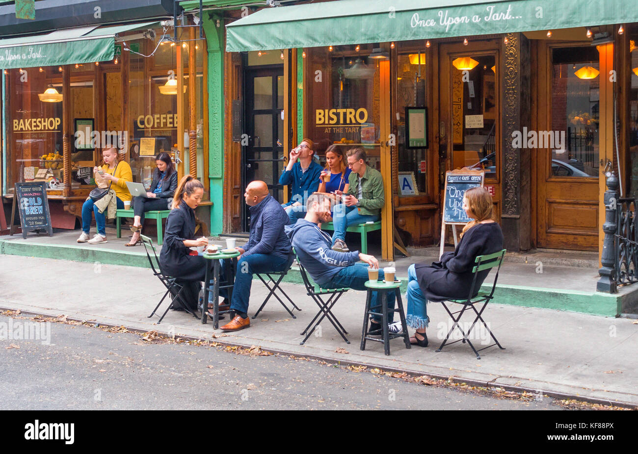 Le persone gustano spuntini e bevande ai tavoli all'aperto di Once Upon A Tart a SoHo a New York Foto Stock