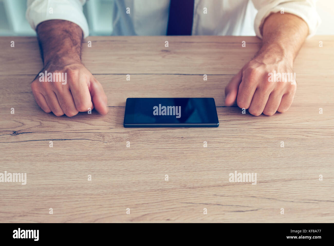 Imprenditore lotta telefono cellulare dipendenza crisi. persona d'affari facendo sforzi per resistere allo smartphone utilizzando il dispositivo sulla scrivania in ufficio. Foto Stock