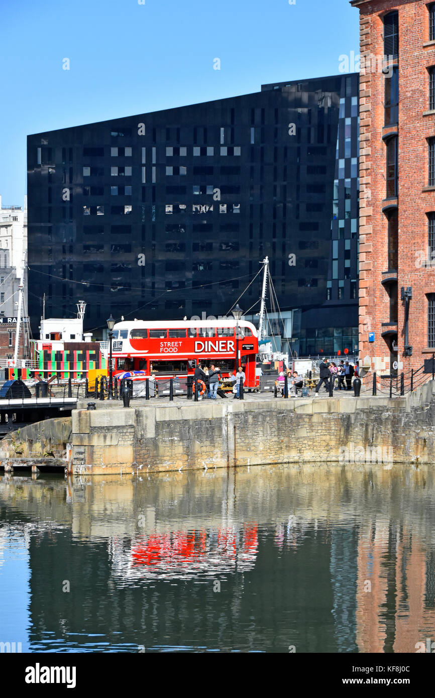 Riflessioni in Liverpool Albert Dock di rosso autobus Routemaster convertito in cafe diner venite restaurant facility nella trafficata area turismo nel Merseyside Regno Unito Foto Stock