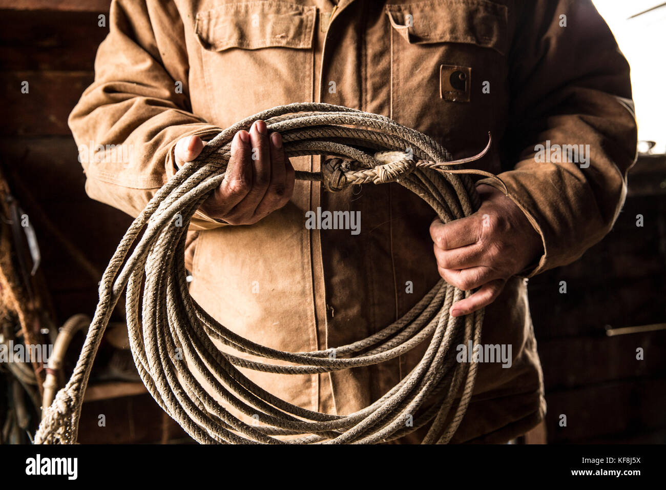 Stati Uniti d'America, oregon, enterprise, cowboy todd nash mantiene la sua corda a snyder ranch dopo una lunga giornata di bovini in movimento sotto la pioggia, nordest oregon Foto Stock