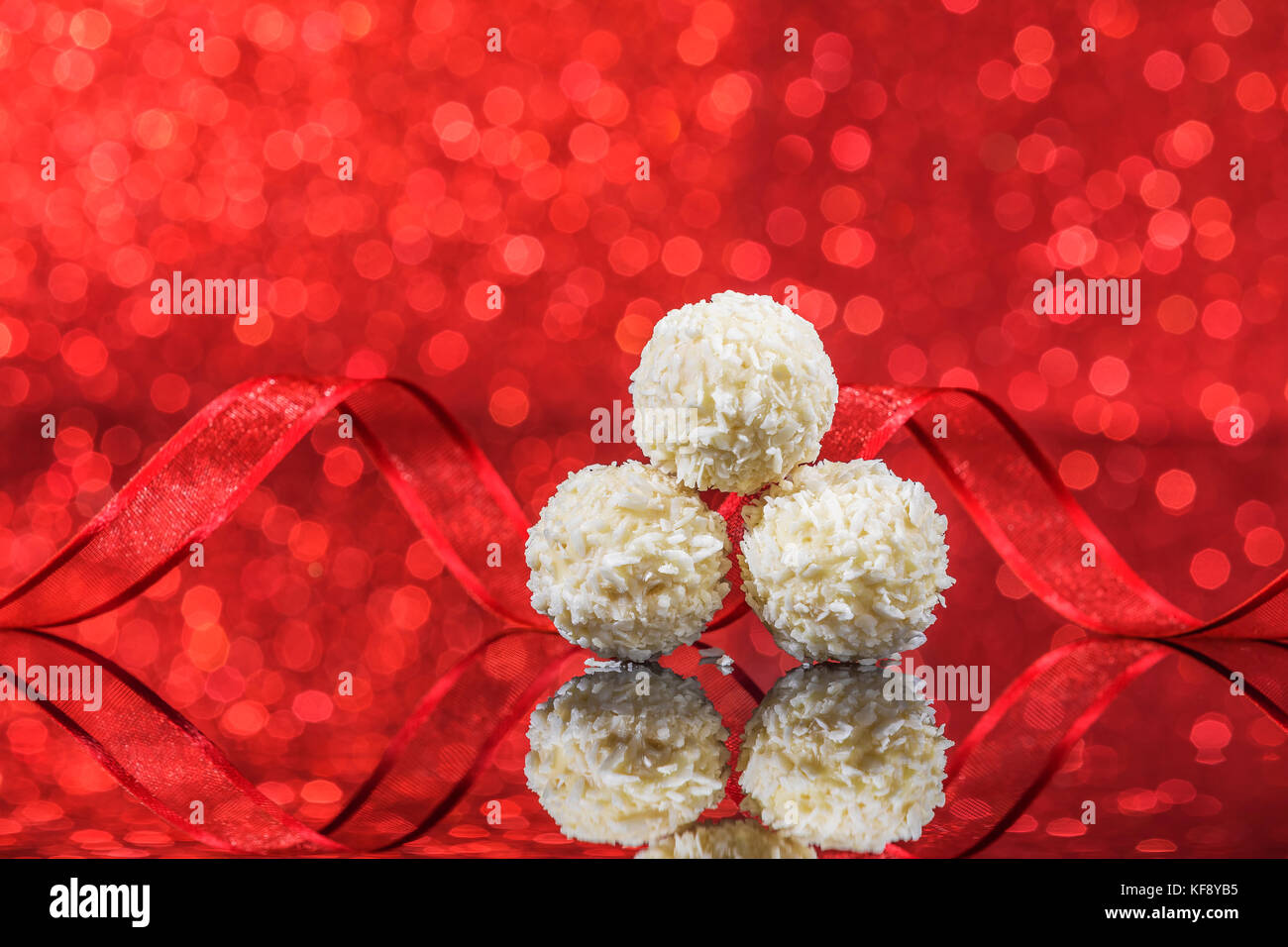 Snowball bianco cioccolato sul tavolo di vetro su rosso bacground con luci glitter Foto Stock