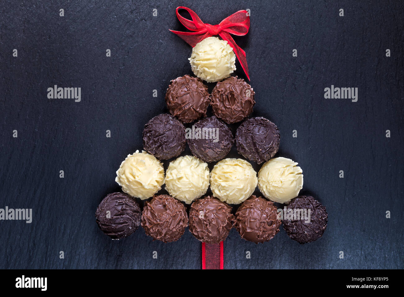 Tartufi di cioccolato forma albero di natale sul nero tavolo in pietra vista superiore Foto Stock