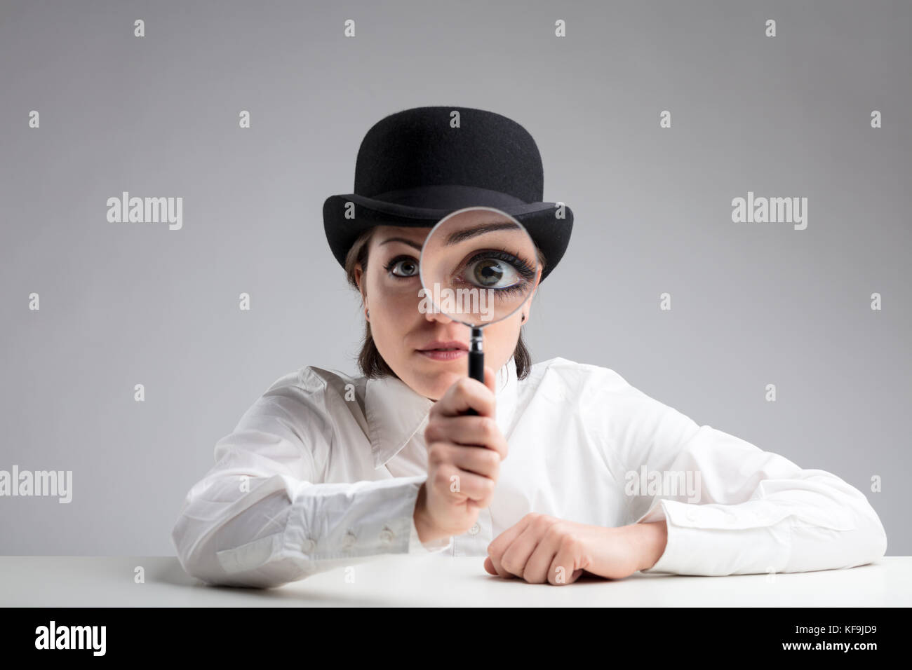 La donna in un Bowler cappello con il suo occhio fatto grande dietro una  lente di ingrandimento di grande significato sospetto o cercare  informazioni Foto stock - Alamy