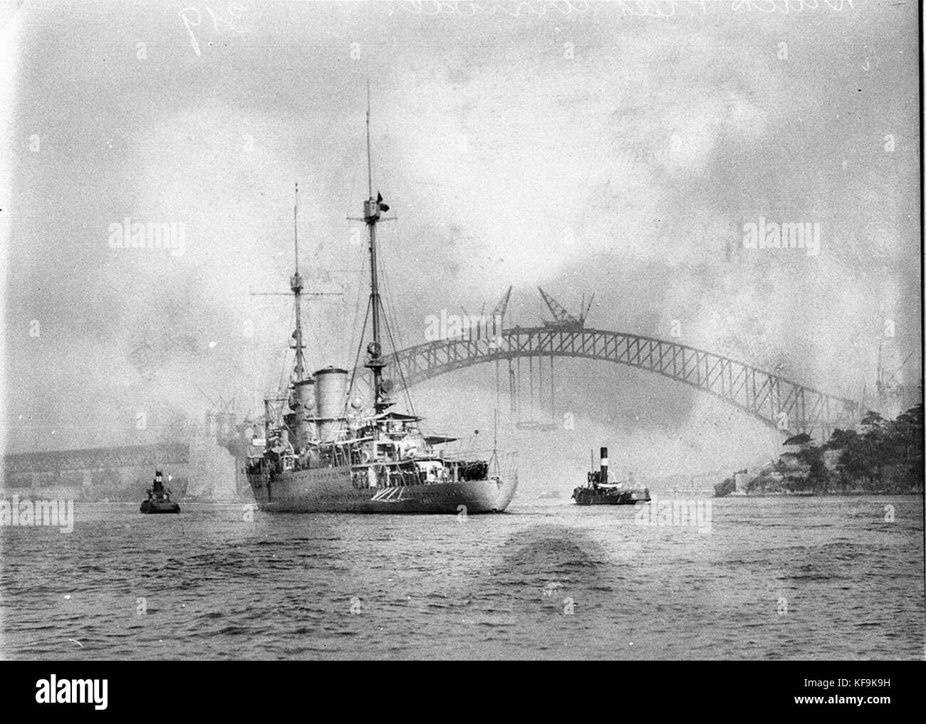 Questa immagine mostra la nave da guerra Java delle Indie Orientali olandesi, ormeggiata con un ponte sullo sfondo. L'immagine riflette il ruolo della nave nella storia navale durante l'era degli imperi coloniali. Foto Stock