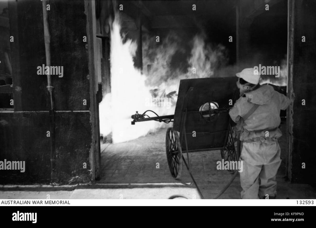 132593 un operaio giapponese indossa una maschera a gas dirige getti DA UN MOBILE LANCIAFIAMME VERSO IL PALO DI BENZINA imbevuto detriti all'interno dell'edificio e in pochi secondi l'interno dell'edificio era un RA 0146 Foto Stock