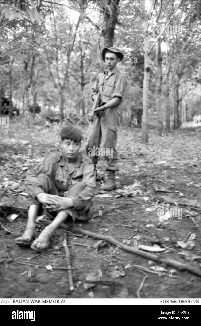 Australian soldato di guardia un Viet Cong prisioner catturata a lunga Tan (AWM PER660659VN) Foto Stock