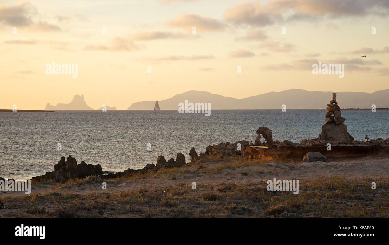 Tramonto con pile di pietra a Spiaggia di Ses Illetes con Es Vedrá e isole ibiza in background da Formentera (Isole Baleari, Spagna) Foto Stock