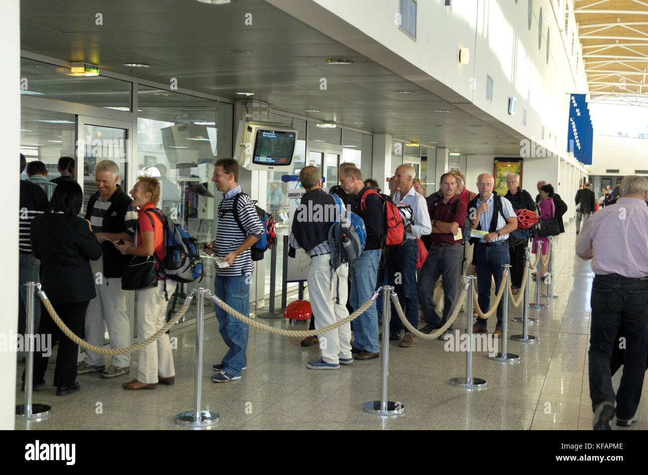 I passeggeri con bagaglio a mano sacchetti code al check-in di sicurezza nel terminale Foto Stock