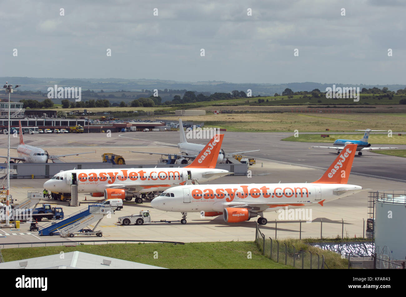 Due easyJet Airbus A319-100s parcheggiato sul piazzale di sosta con veicoli aeroportuali e airstairs Foto Stock