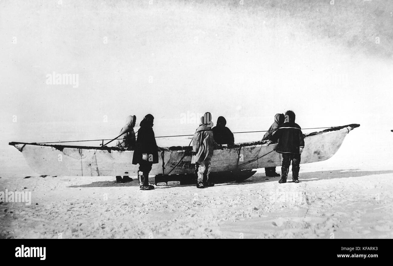 Sei eschimesi in piedi accanto a skinboat nativo (umiak) sulla slitta, punto Barrow, Alaska Foto Stock