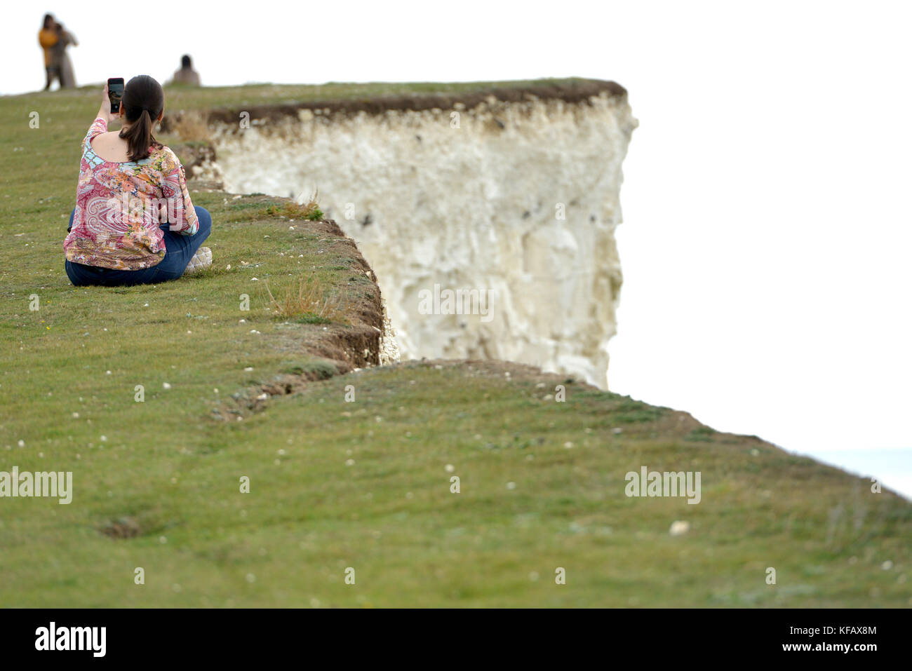 I turisti tenendo rischioso selfies sul confine di una scogliera di sette sorelle a Birling Gap, East Sussex. Foto Stock