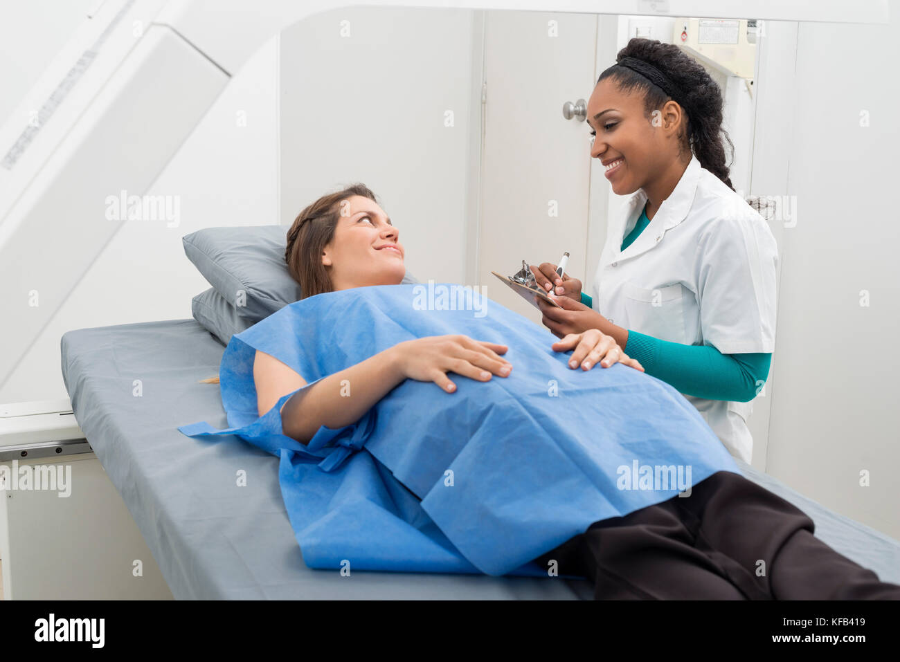 Radiologo iscritto sulla clipboard mentre guardando il paziente in hos Foto Stock