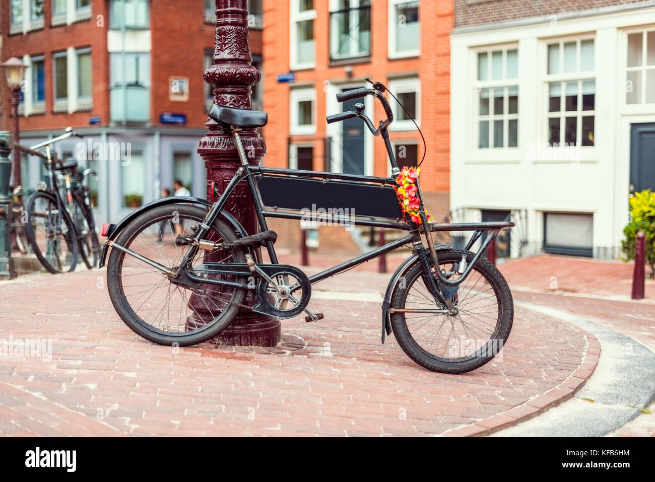 Bicicletta parcheggiata contro e bloccato per via la luce in una strada di Amsterdam Paesi Bassi Foto Stock