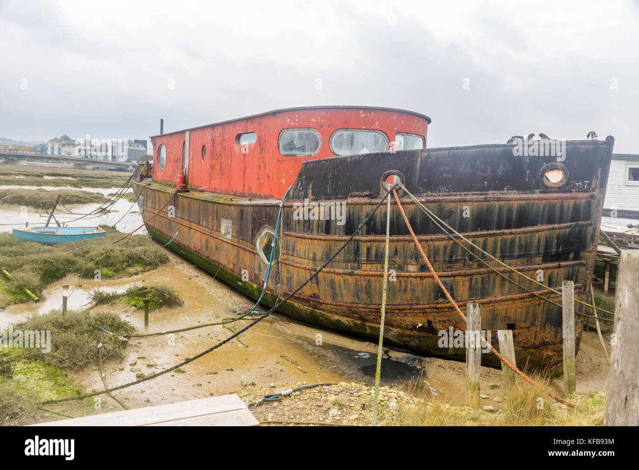 Rimorchiatore di metallo recuperato per la casa galleggiante sulla riva del fiume Foto Stock