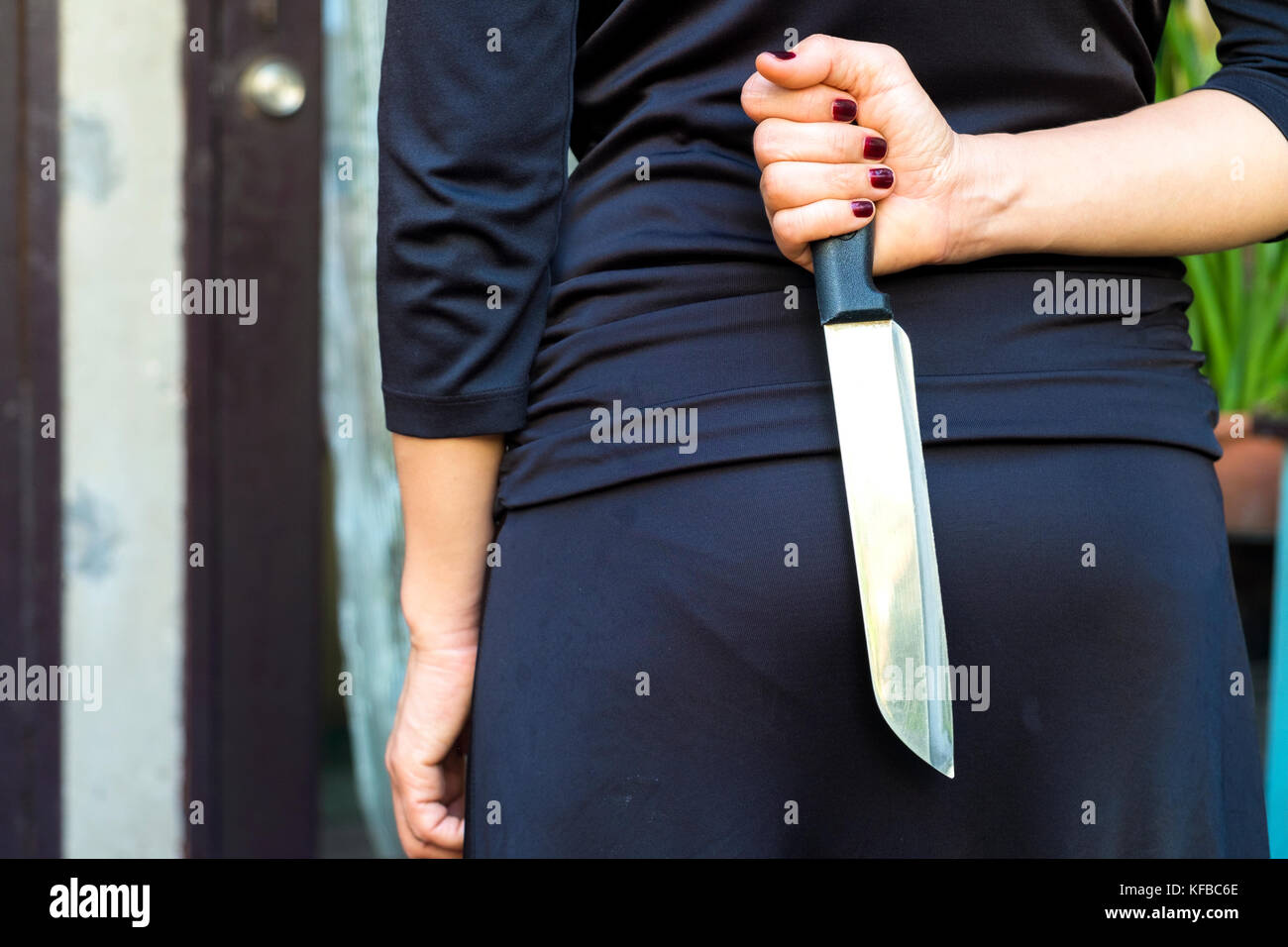 La donna in nero che tiene un coltello nascosto dietro Foto stock