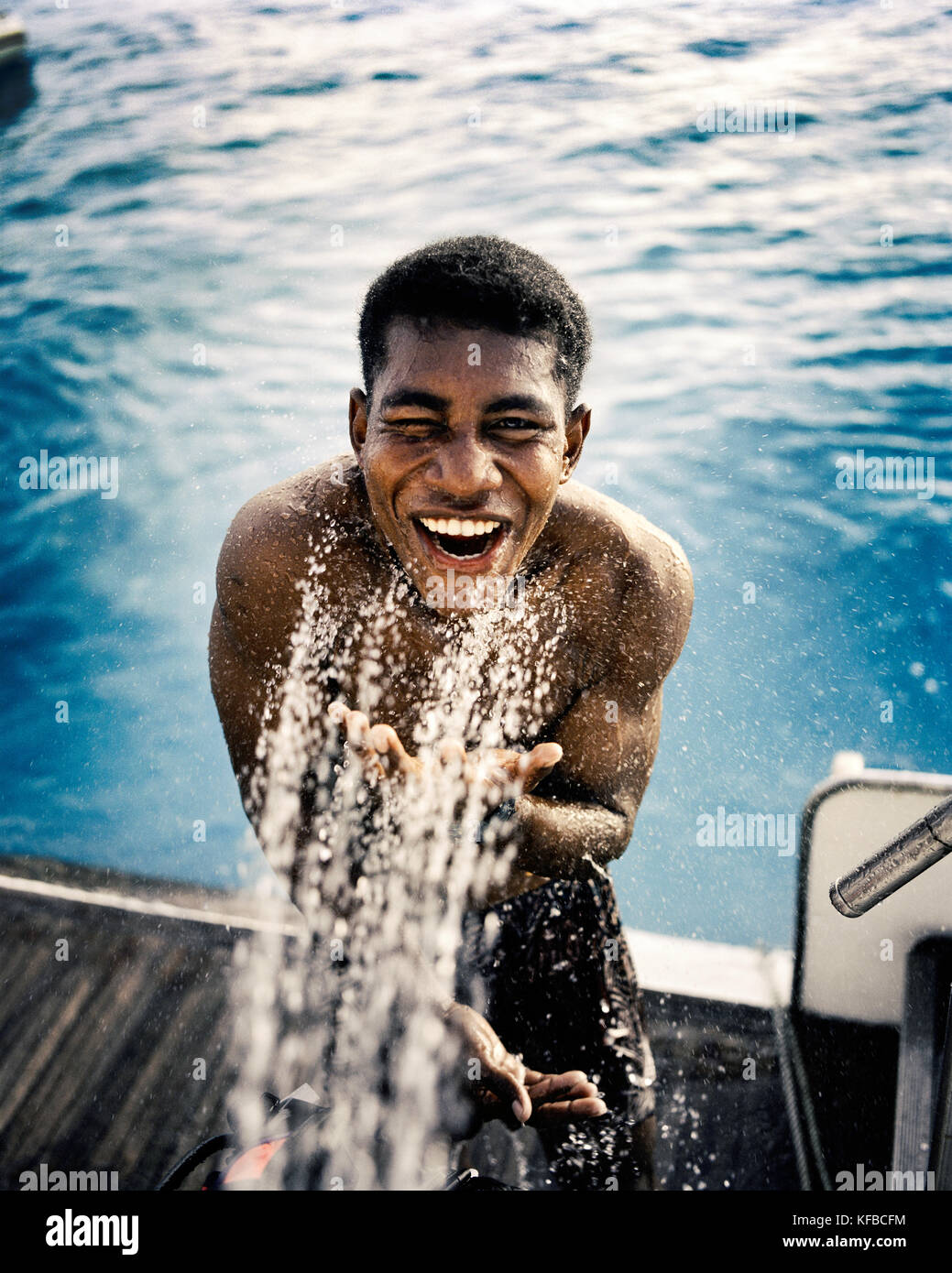 Isole Figi, northern lau isole, un giovane uomo prende un risciacquo sul retro ponte di una barca da pesca Foto Stock