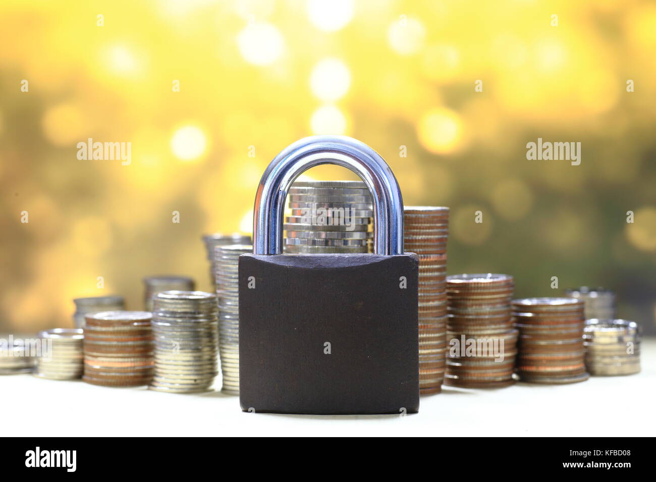 Coin pila di denaro e la serratura e oro su sfondo chiaro. Salvataggio e sicurezza finanziaria concetto. Foto Stock