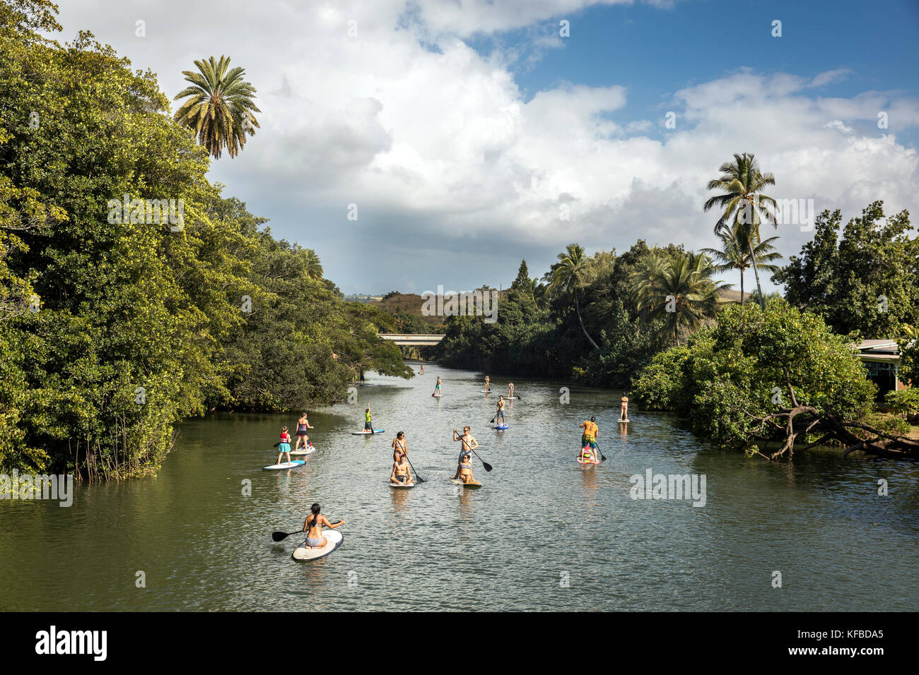 HAWAII, Oahu, North Shore, viaggiatori paddleboarding sul fiume Anahulu sotto lo storico Ponte di Arcobaleno nella città di Haliewa Foto Stock