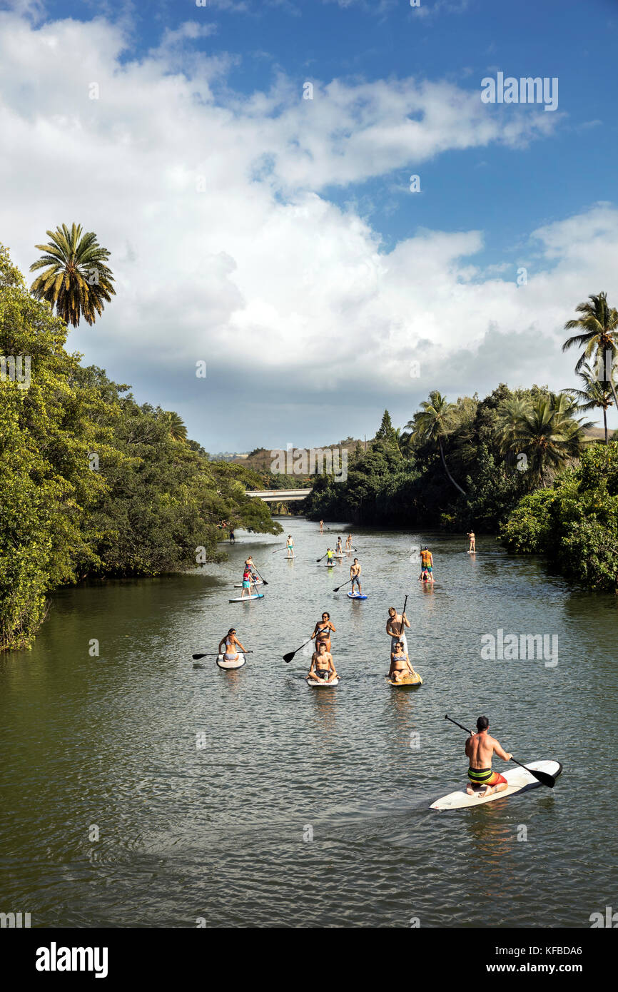HAWAII, Oahu, North Shore, viaggiatori paddleboarding sul fiume Anahulu sotto lo storico Ponte di Arcobaleno nella città di Haliewa Foto Stock