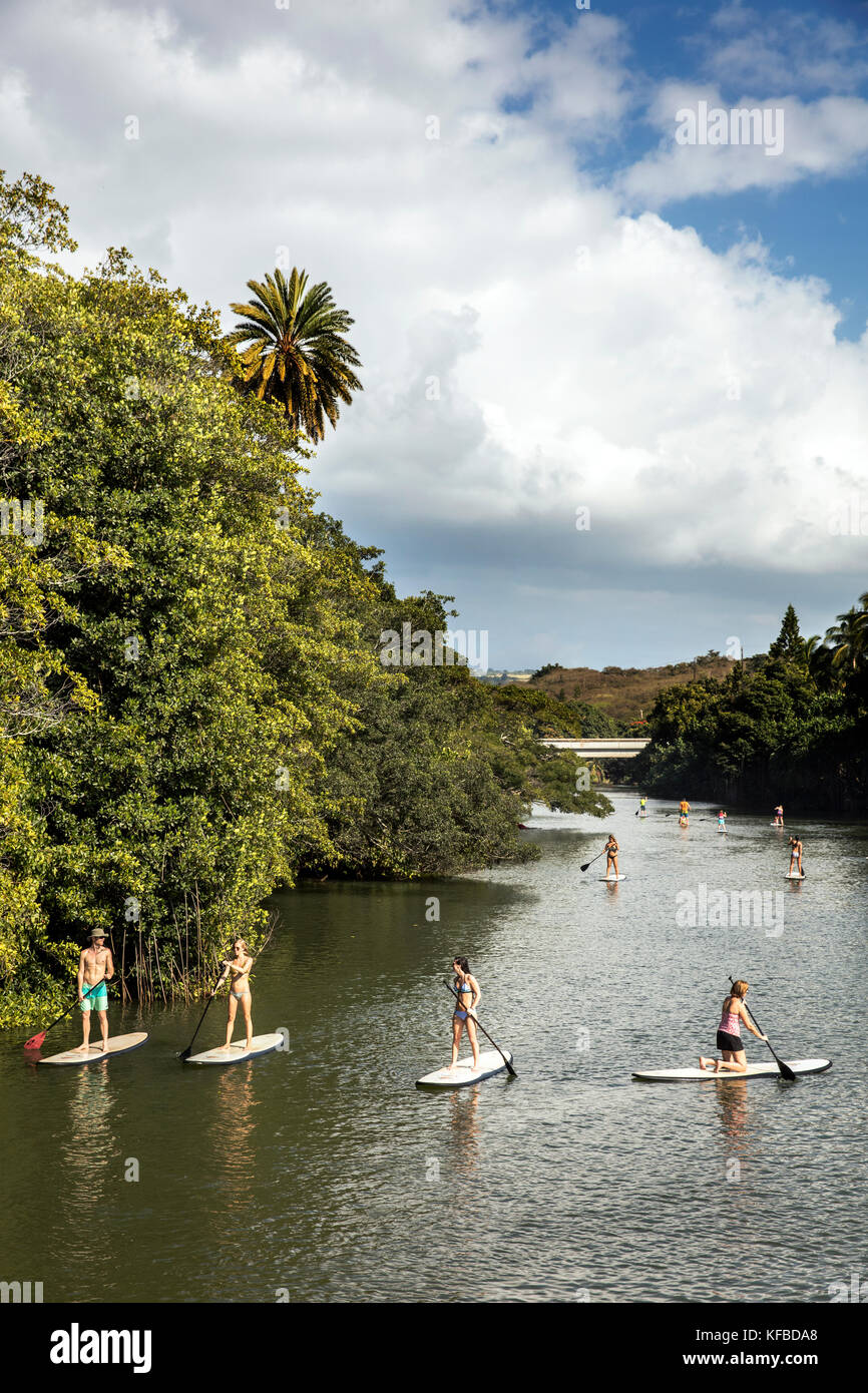 HAWAII, Oahu, North Shore, viaggiatori paddleboarding sul fiume Anahulu sotto lo storico Ponte di Arcobaleno nella città di Haliewa Foto Stock