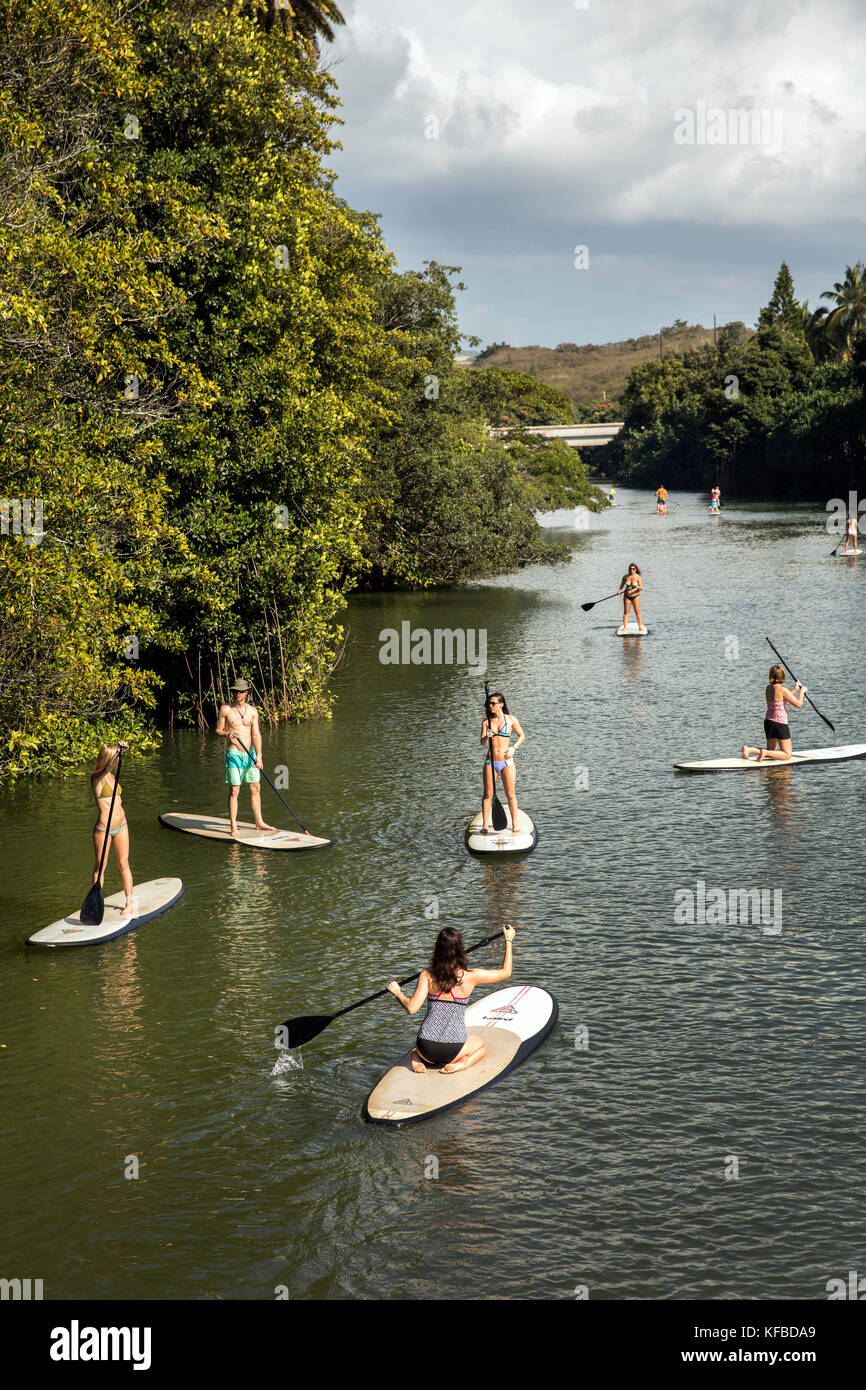 HAWAII, Oahu, North Shore, viaggiatori paddleboarding sul fiume Anahulu sotto lo storico Ponte di Arcobaleno nella città di Haliewa Foto Stock