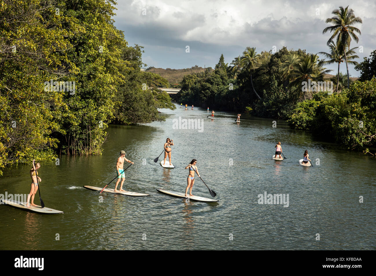 HAWAII, Oahu, North Shore, viaggiatori paddleboarding sul fiume Anahulu sotto lo storico Ponte di Arcobaleno nella città di Haliewa Foto Stock