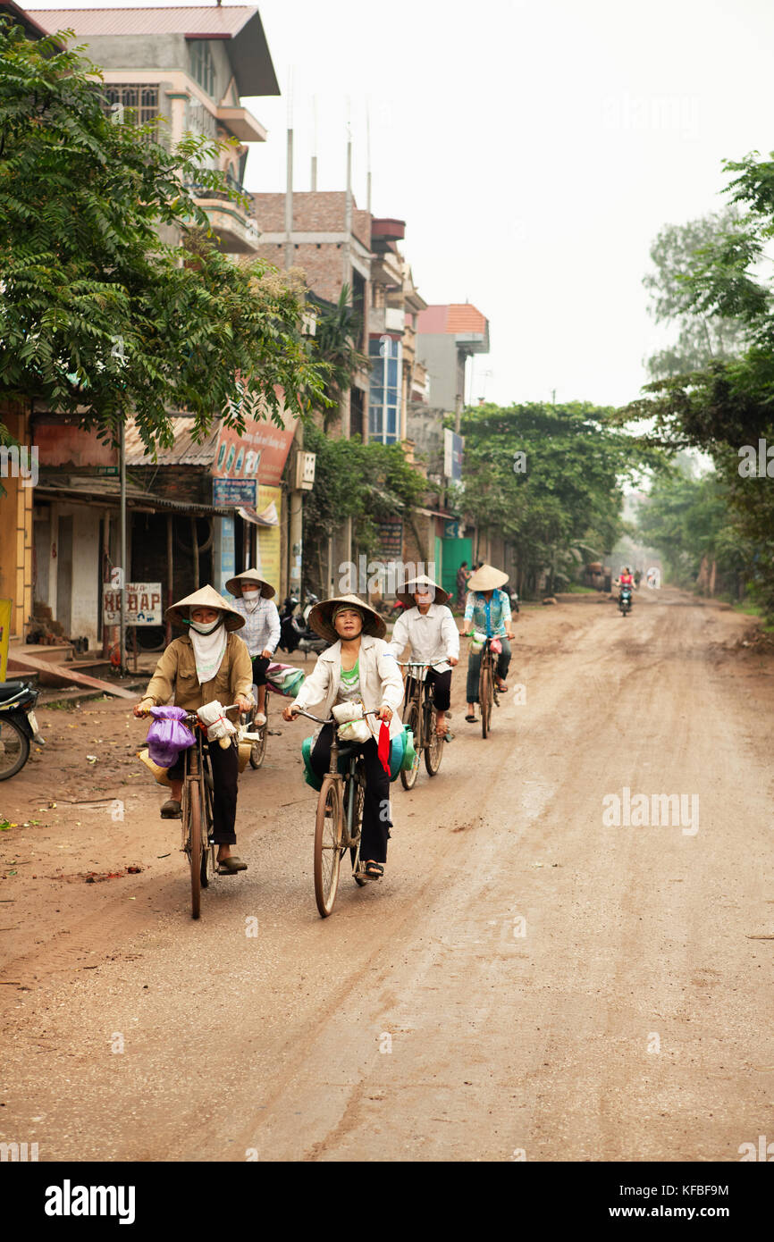 Il Vietnam, Hanoi, campagna, donne cavalcare le loro biciclette lungo una strada rurale in thanh Bac Ninh Foto Stock