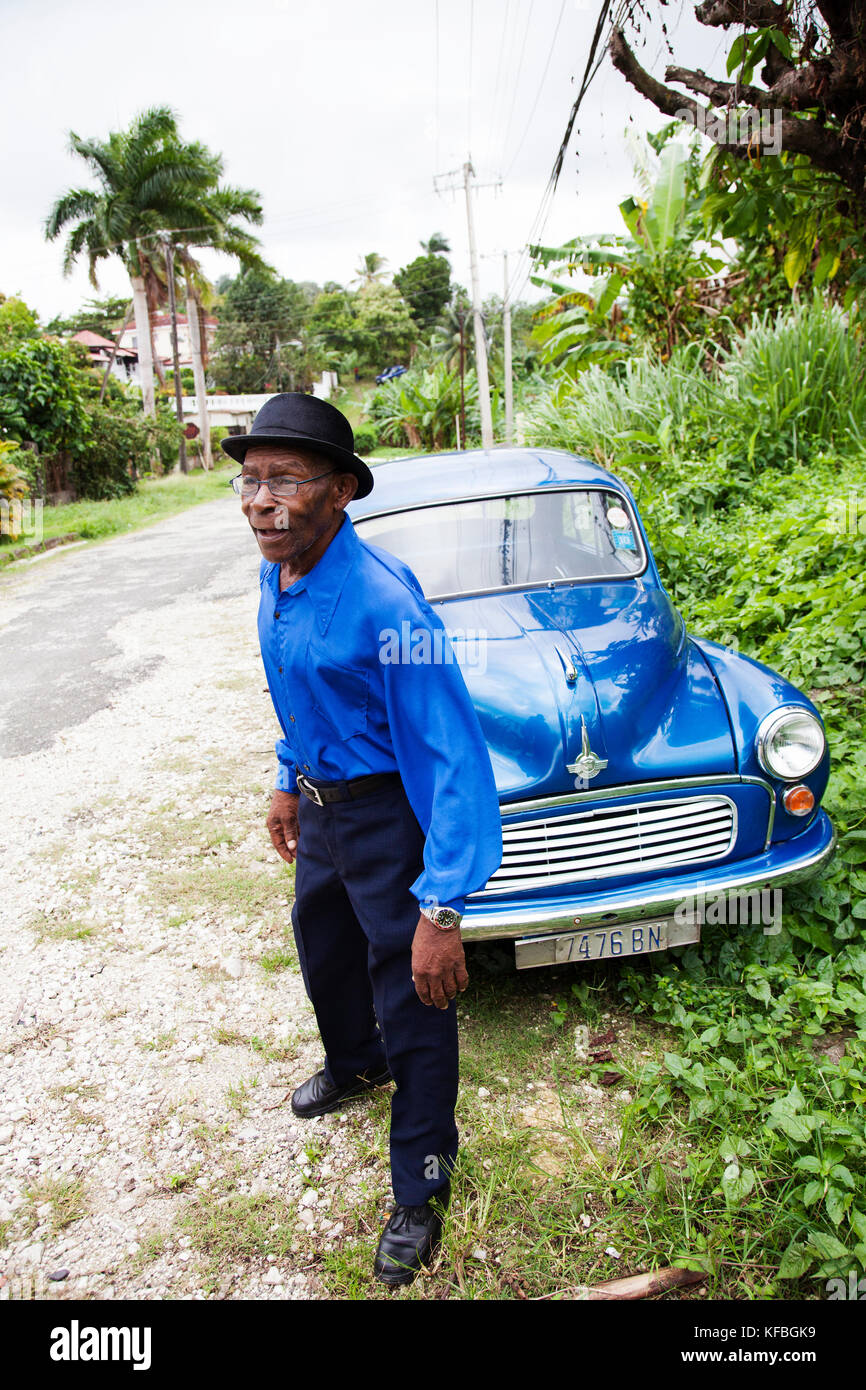 Giamaica, Port Antonio. Giuseppe " polveri " Bennett del Mento Band, il Jolly Boys in piedi di fronte a un vintage auto blu. Foto Stock