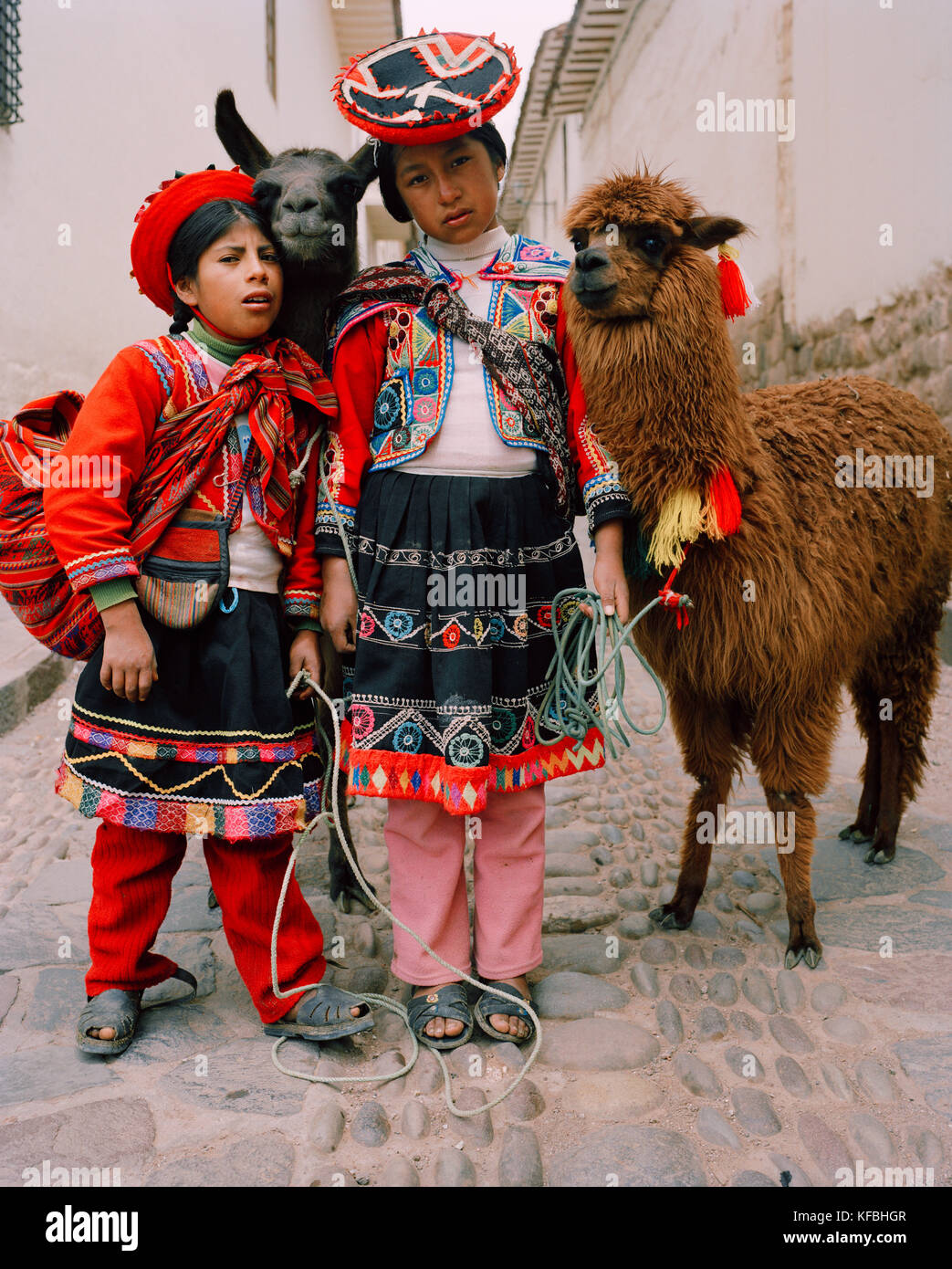 Perù Cusco, Sud America, America Latina, ragazze che indossano abiti tradizionali in piedi con la lama in una strada in Cusco. Foto Stock
