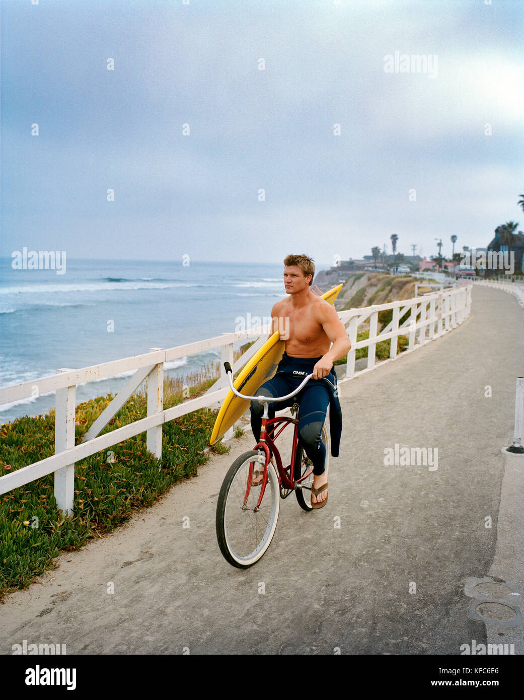 Stati Uniti, California, surfer in bicicletta con la sua tavola da surf sul lungomare a piacere il punto, santa cruz Foto Stock