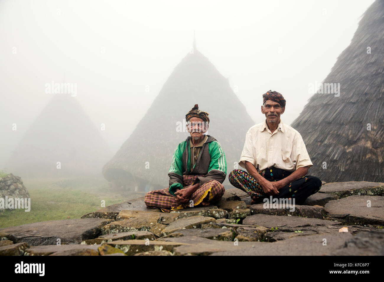 Indonesia, Flores, due leader della wae rebo village sedersi di fronte a loro residenze chiamato mbaru niang Foto Stock