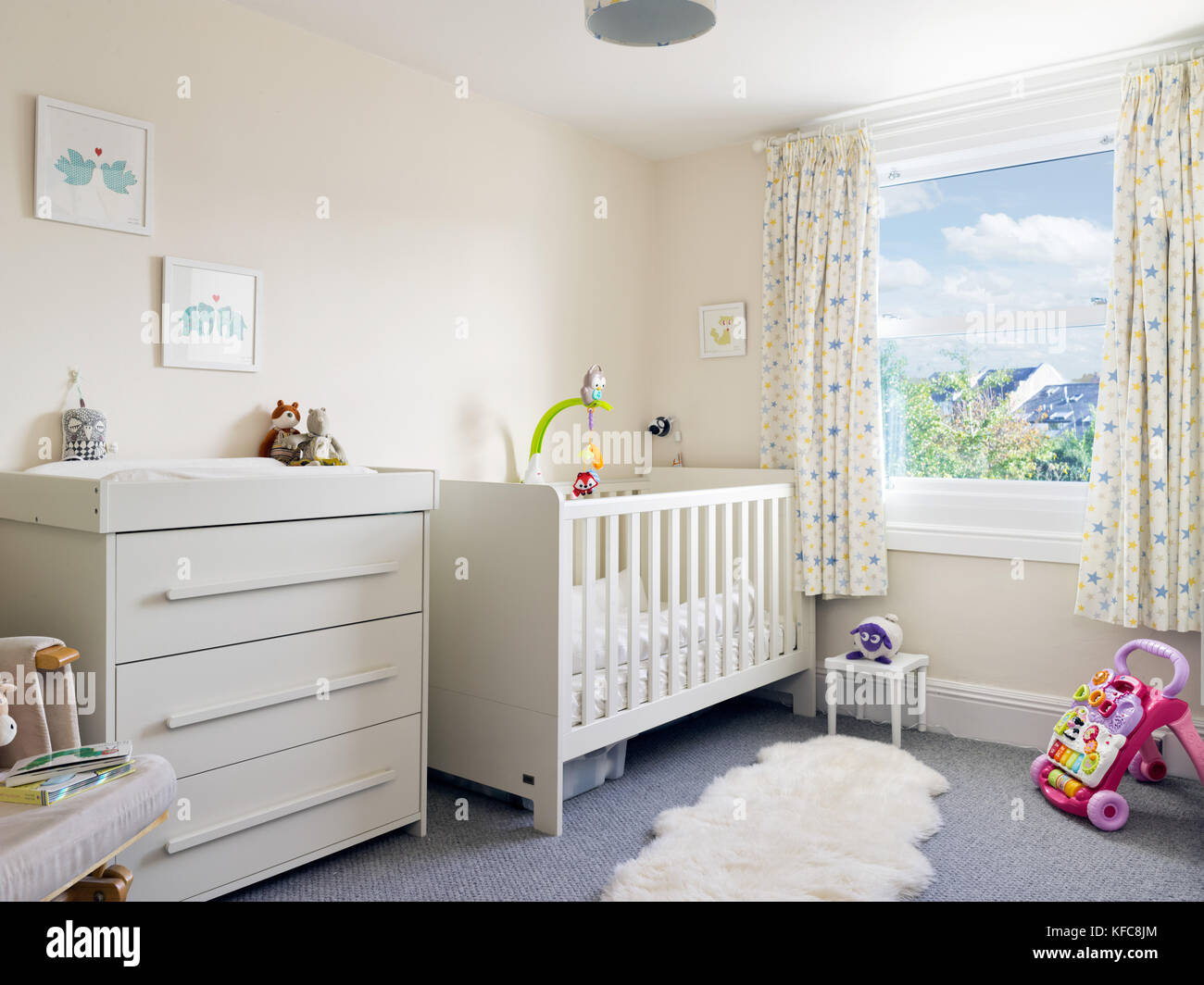 Un moderno, pulito e ordinato per bambini nursery room decorate in un contemporaneo stile include un lettino e fasciatoio. Foto Stock