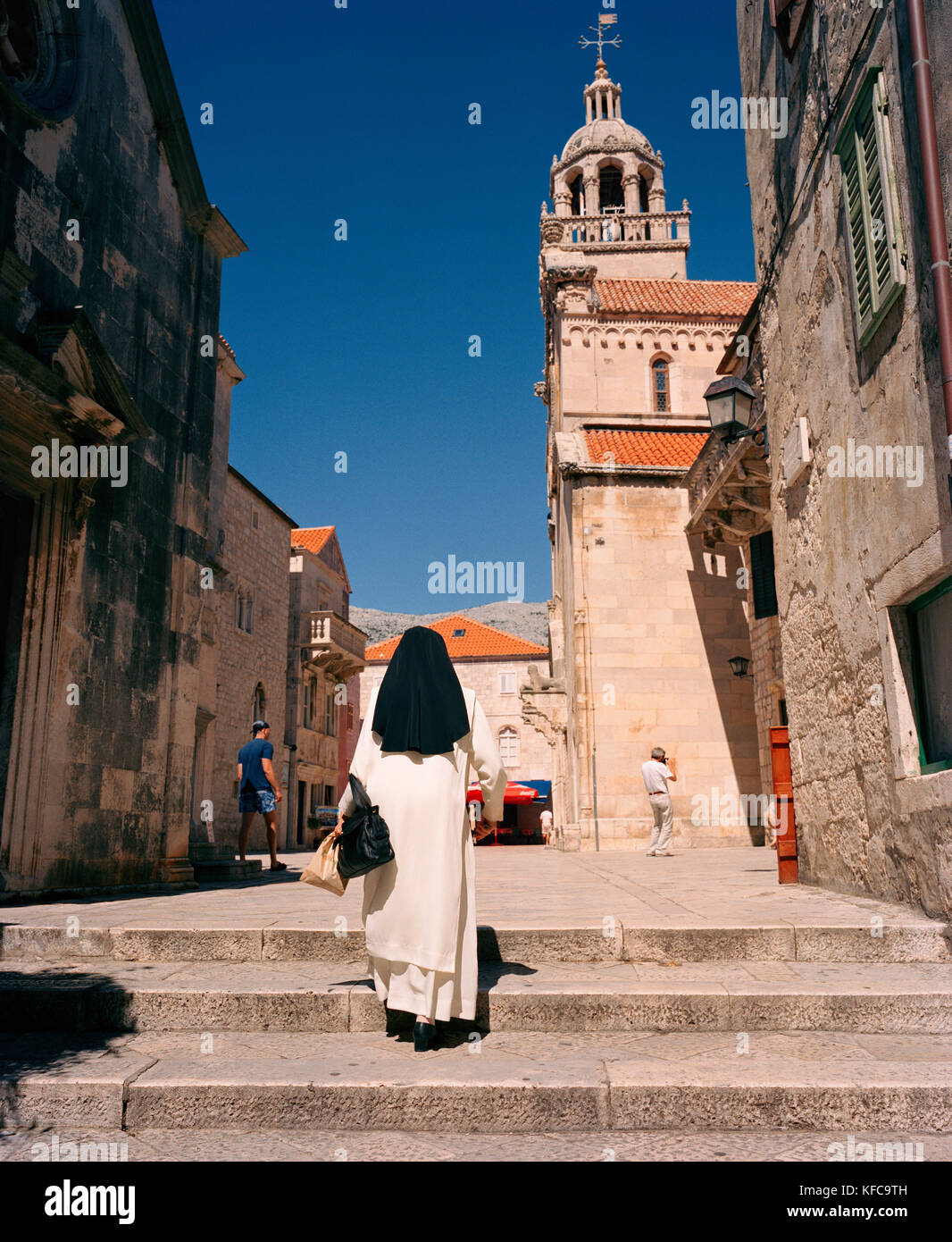 Croazia Korcula costa dalmata, isola, vista posteriore di una monaca in cammino verso la chiesa Foto Stock