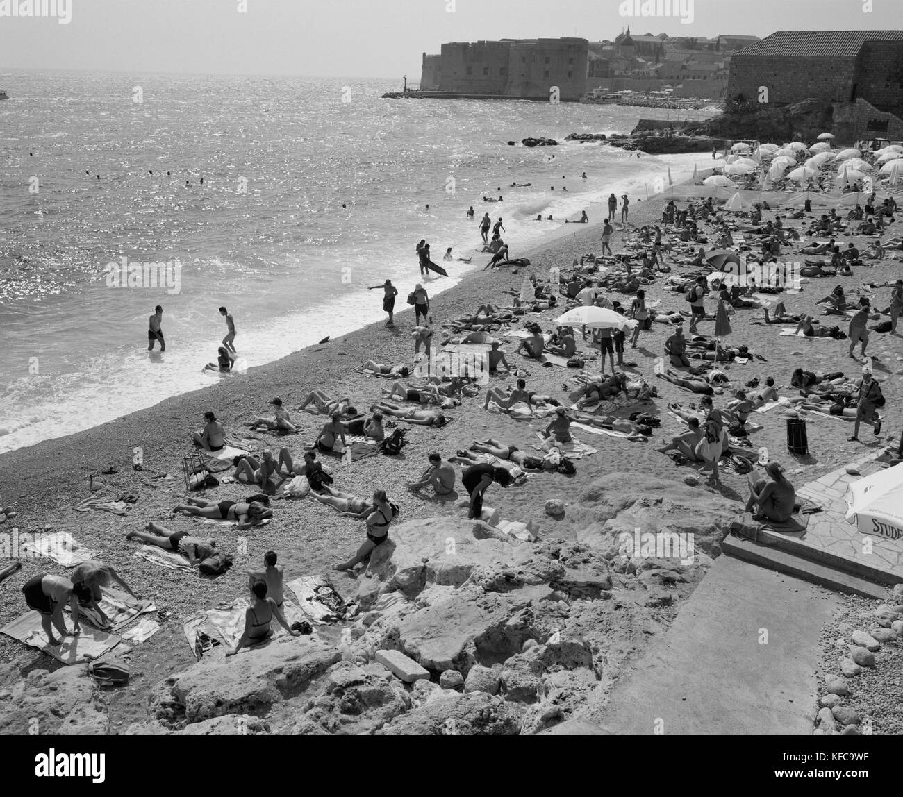Croazia, Dubrovnik, costa dalmata, rilassante a East West Beach con la vecchia città di Dubrovnik in background in B/W. Foto Stock