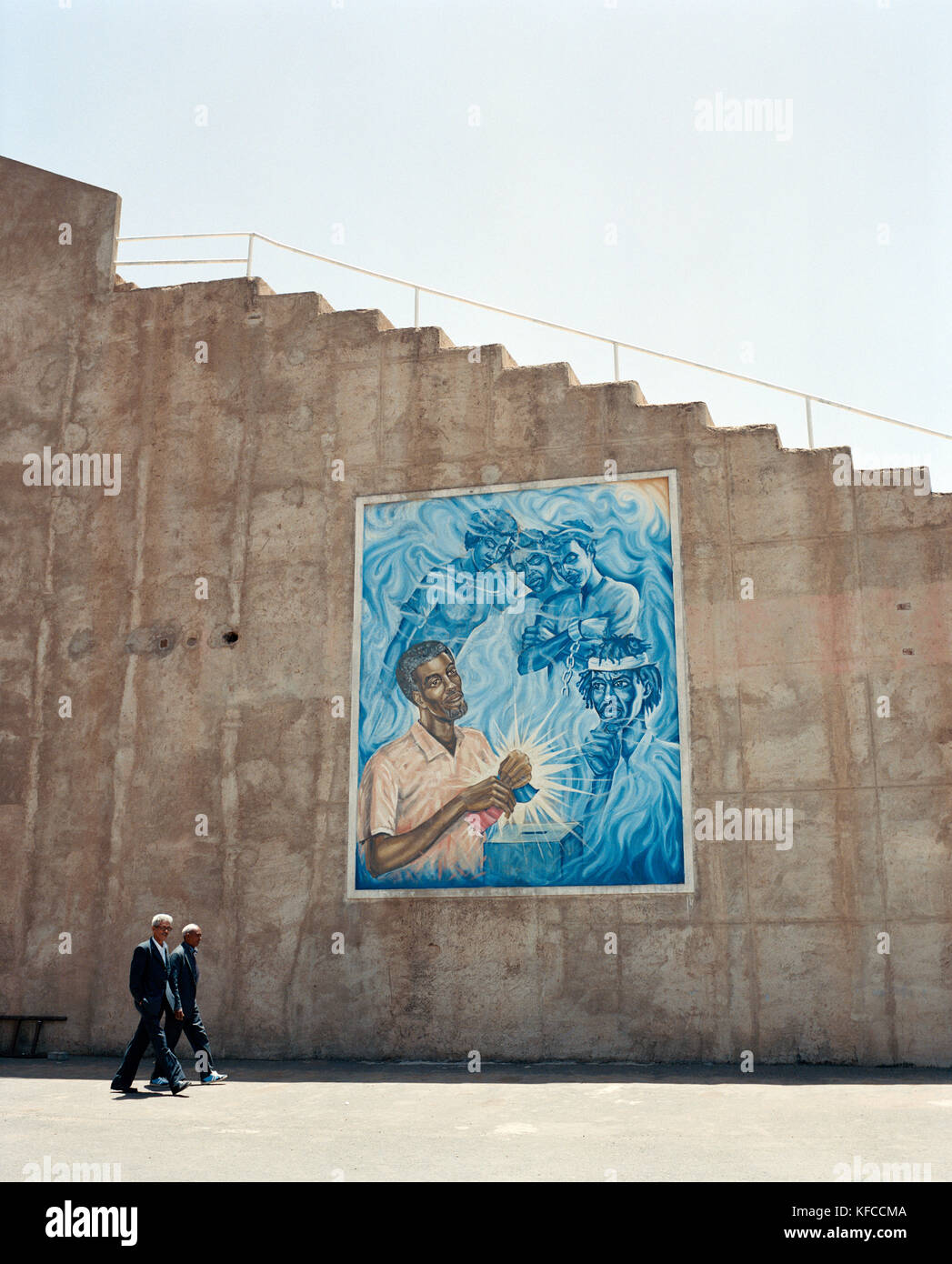 ERITREA, Asmara, uomini d'affari camminano accanto a murales raffiguranti la guerra Eritrea-Etopia Foto Stock