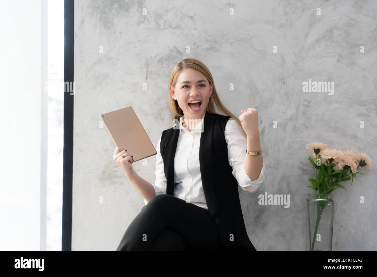 Felice imprenditrice con alzata nel gesto sì lettura mano compressa alla scrivania in ufficio. femmina gioia imprenditore buone notizie da corrispondenza. exi Foto Stock