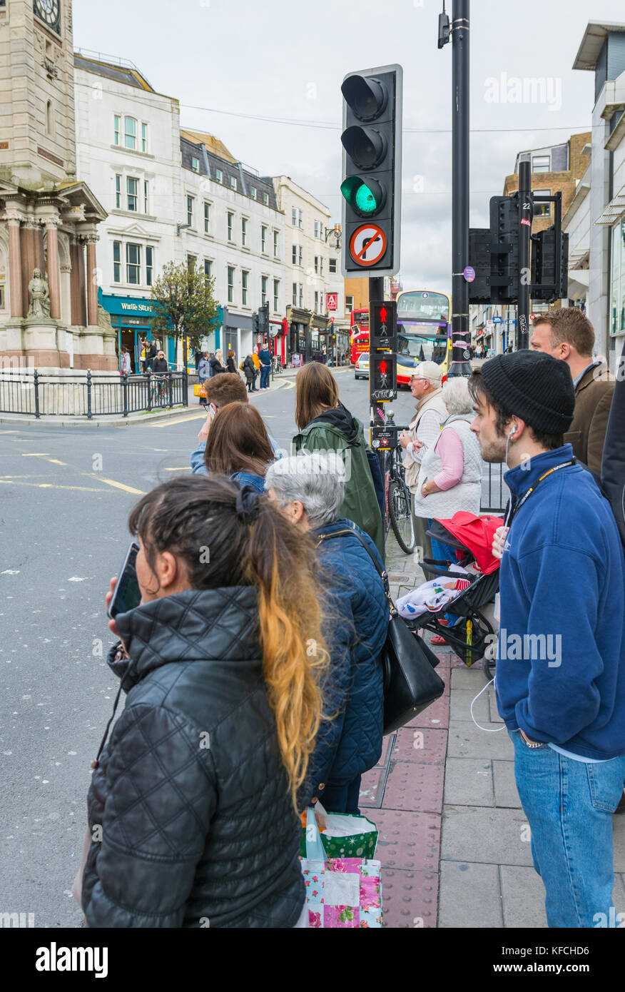 Le persone in attesa di attraversare una strada in corrispondenza di luci pedonale in Brighton, East Sussex, Inghilterra, Regno Unito. Foto Stock