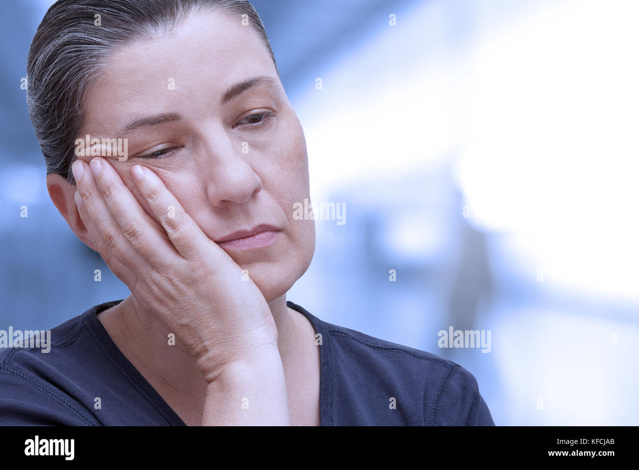 Donna di mezza età quasi addormentarsi in ufficio. Stanchezza a causa della sindrome da apnea nel sonno, insonnia o fibromialgia, blu per effetto del filtro Foto Stock