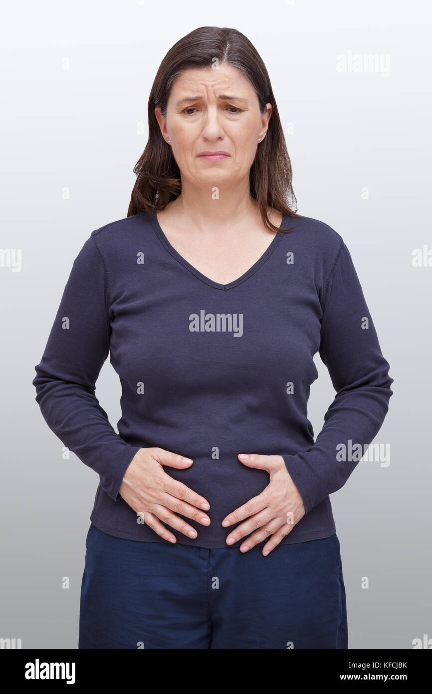 Donna di mezza età con una accorata espressione sul viso premendo le mani sul suo ventre, mal di pancia causato da intolleranza alimentare Foto Stock