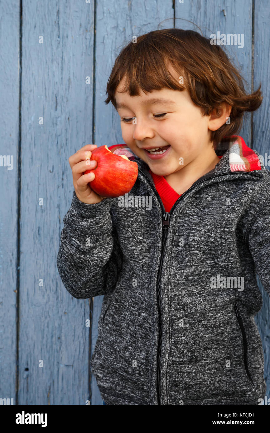 Bambino kid mangiare frutta Apple sorridenti outdoor autunno cadono all'esterno sano Foto Stock