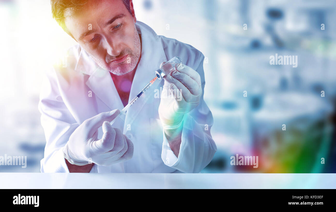 Scienziato studiando i trattamenti per la cura di malattie con la siringa ed il flaconcino in mani dietro un tavolo bianco. Composizione orizzontale Foto Stock