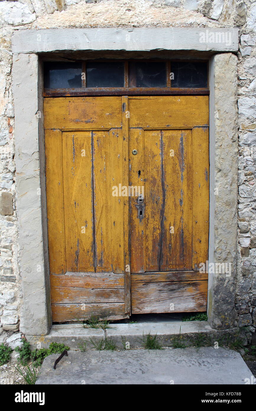 Vecchie gialle di porte in legno con piccole top in vetro windows e pietra  pesante telaio messo in tradizionale muro di pietra Foto stock - Alamy