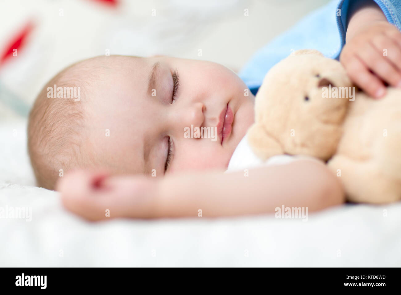 Bambino bambini in letto, tenendo un orsacchiotto di peluche. Foto Stock