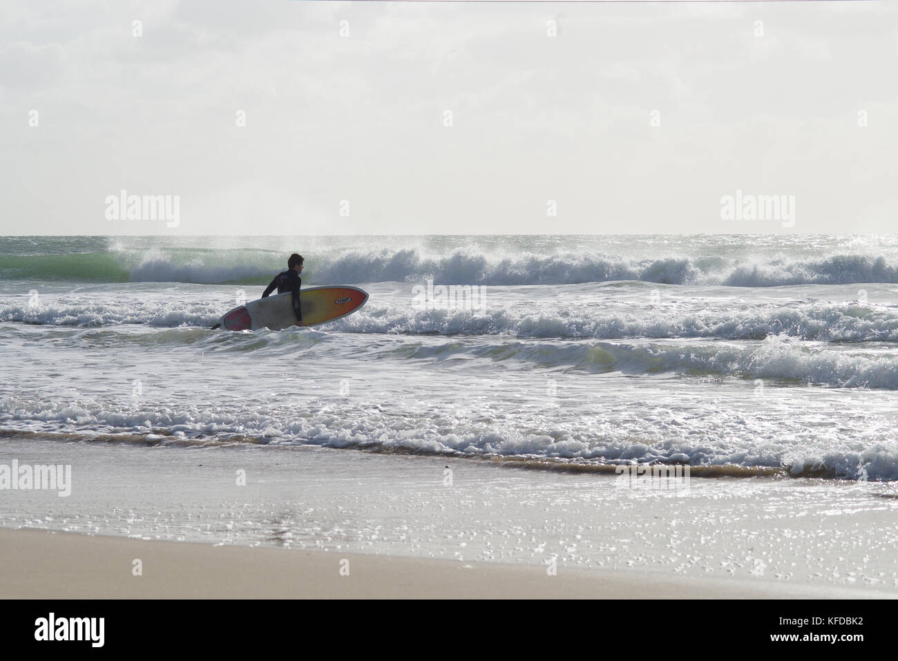 Surfer con scheda presso la spiaggia di Bournemouth Foto Stock