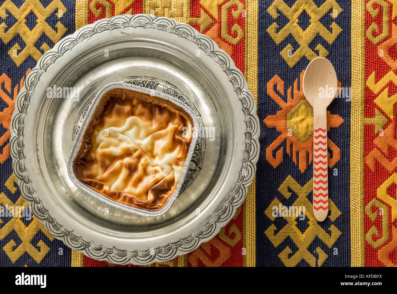 Budino di salita (muhallebi) nella piastra vintage con moquette e cucchiaio vista superiore Foto Stock