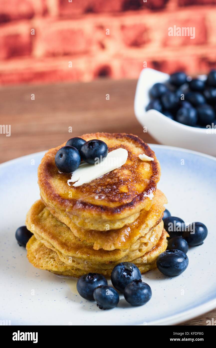 Pila di freschi fatti in casa senza glutine pancake con mirtilli, burro e sciroppo di fronte a un muro di mattoni sfondo Foto Stock