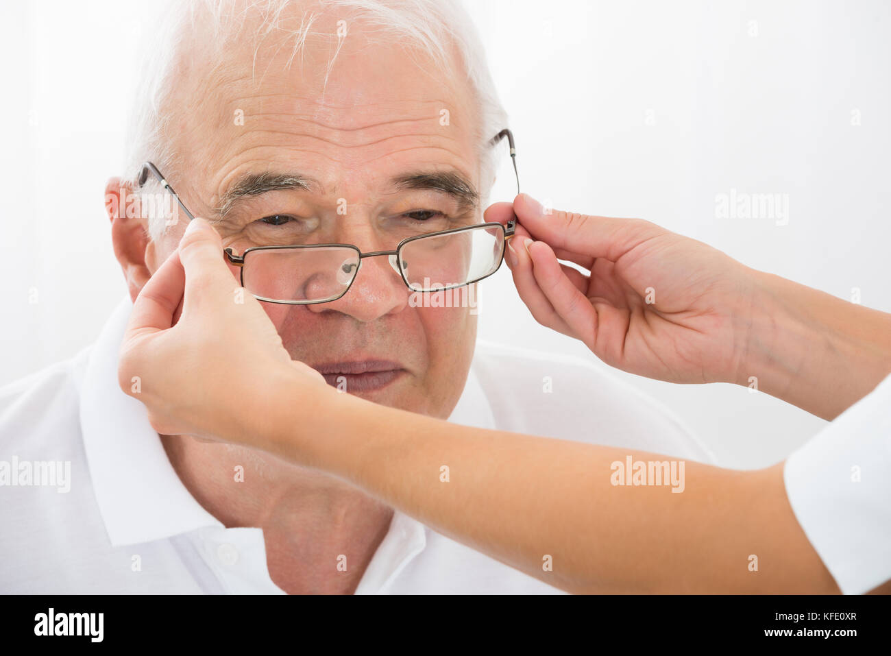 Close-up di un ottico aiutando senior paziente di sesso maschile con nuovi occhiali Foto Stock