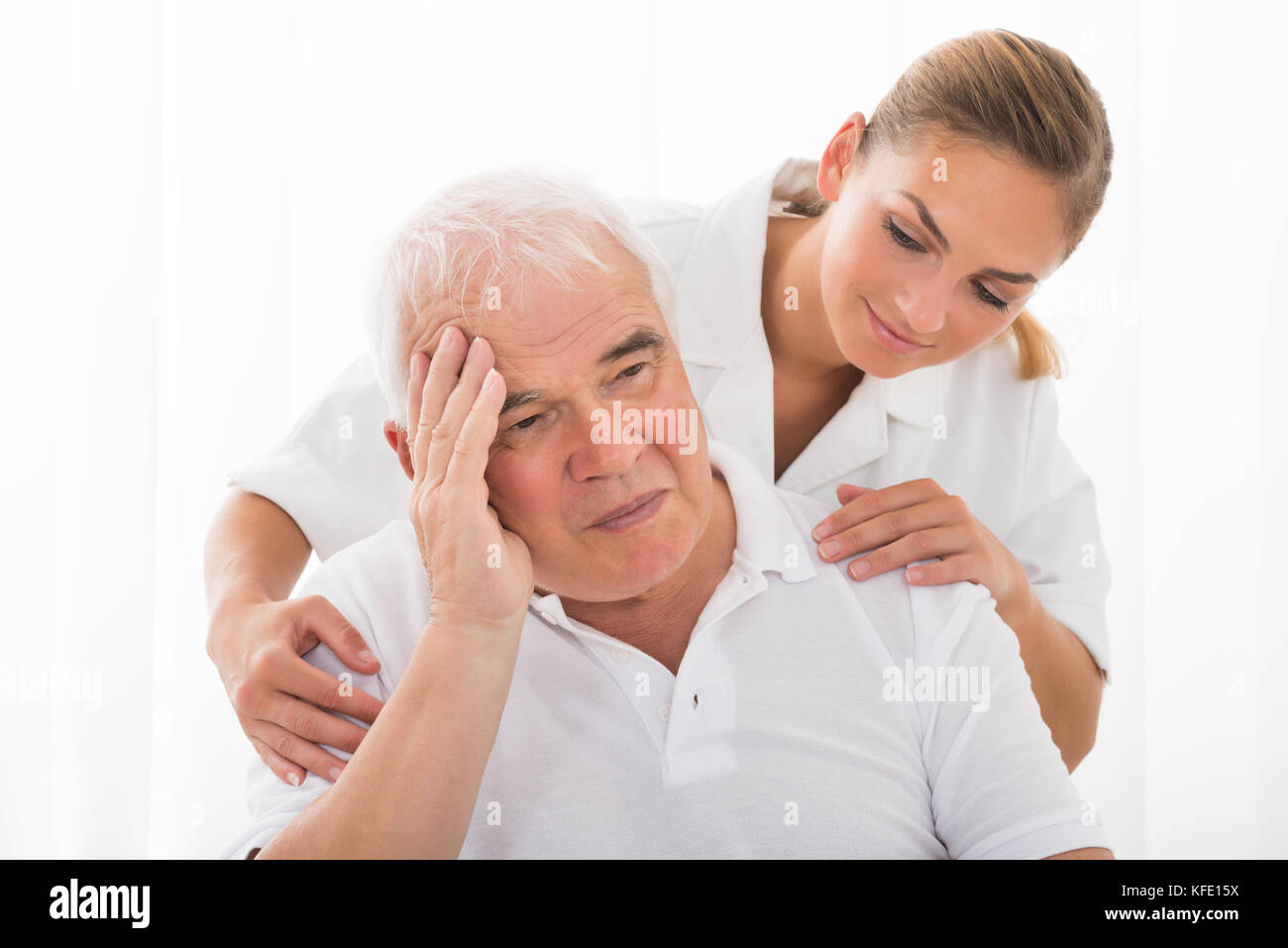 Giovani donne medico consolante triste senior paziente di sesso maschile Foto Stock