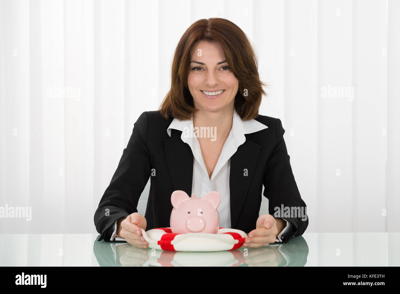 Felice giovane imprenditrice rifugiandosi piggybank con lifebelt Foto Stock